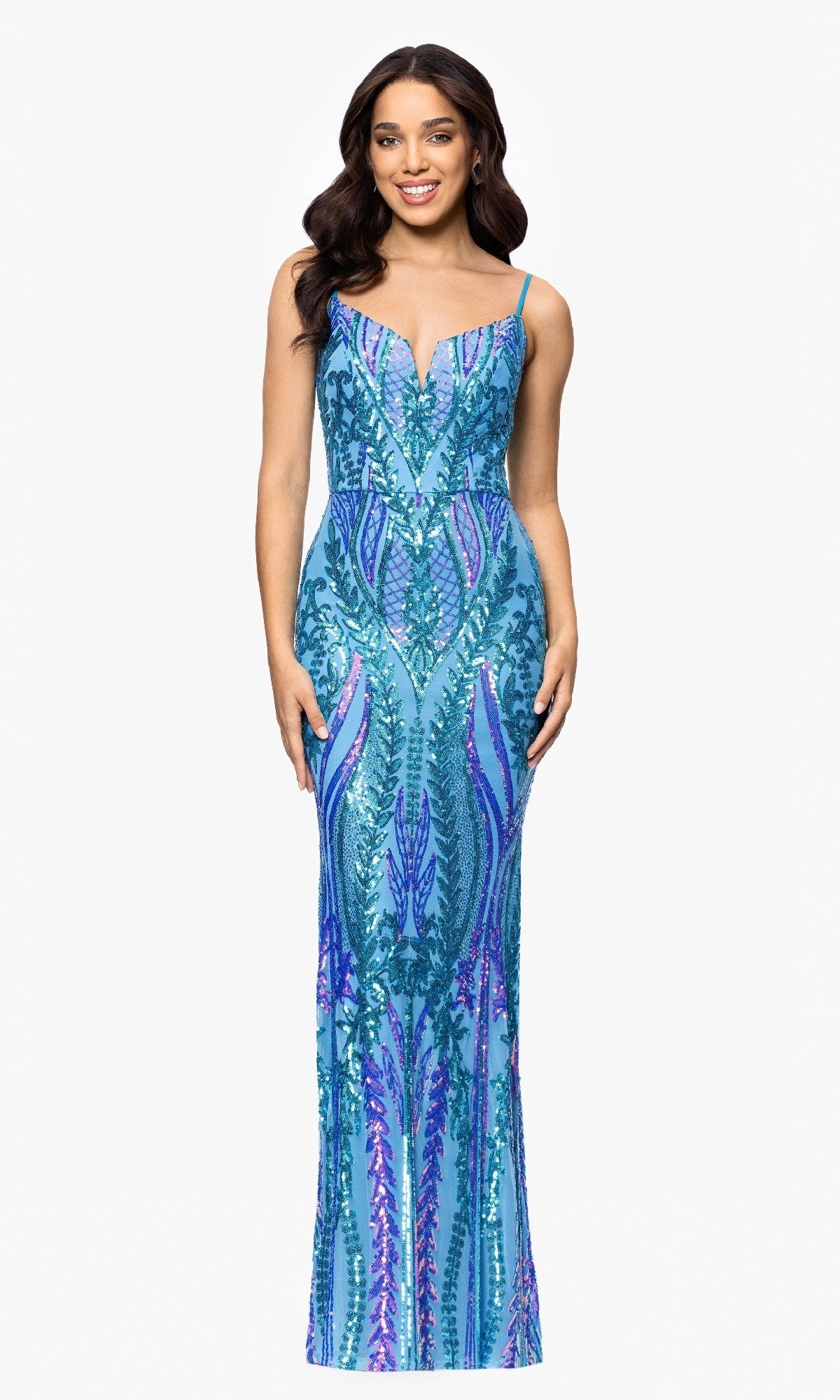 A woman smiles at the camera wearing the Long Sequin-Print Prom Dress: Blondie Nites 5358BN—a fitted, floor-length gown with blue and purple sequins, a plunging neckline, and thin straps.